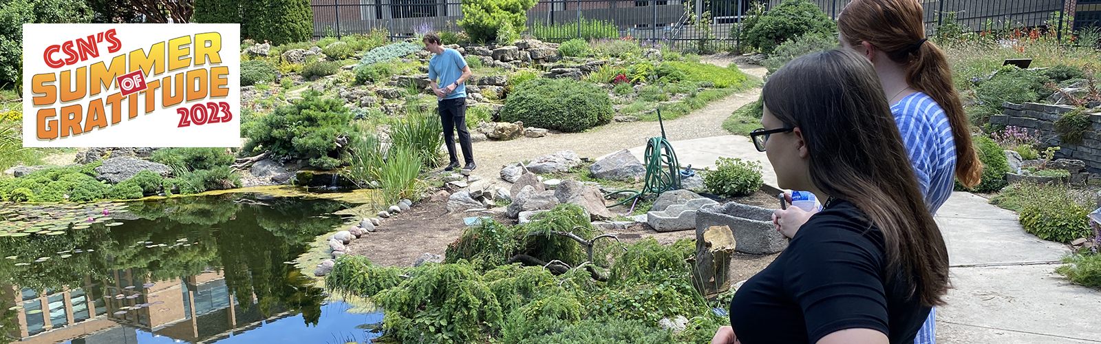 Three people looking into the koi pond at Allen Centennial Gardens on UW-Madison Campus.